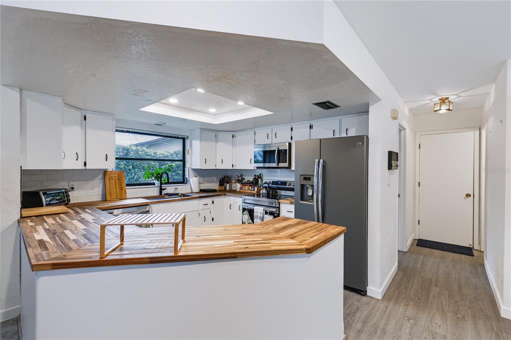 A kitchen with white cabinets, butcher block countertops, stainless steel appliances, and a recessed ceiling light — 9520 LAKE CHRISTINA LANE, PORT RICHEY, FL