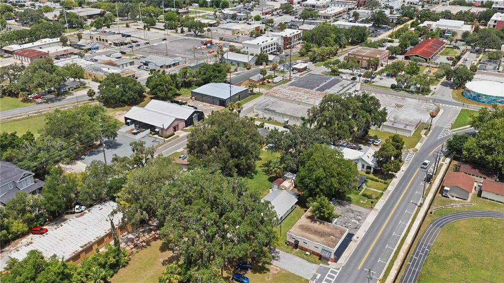 An aerial view shows a neighborhood with commercial buildings, residential houses, and a running track — 1 CENTRAL WAREHOUSE, OCALA, FL