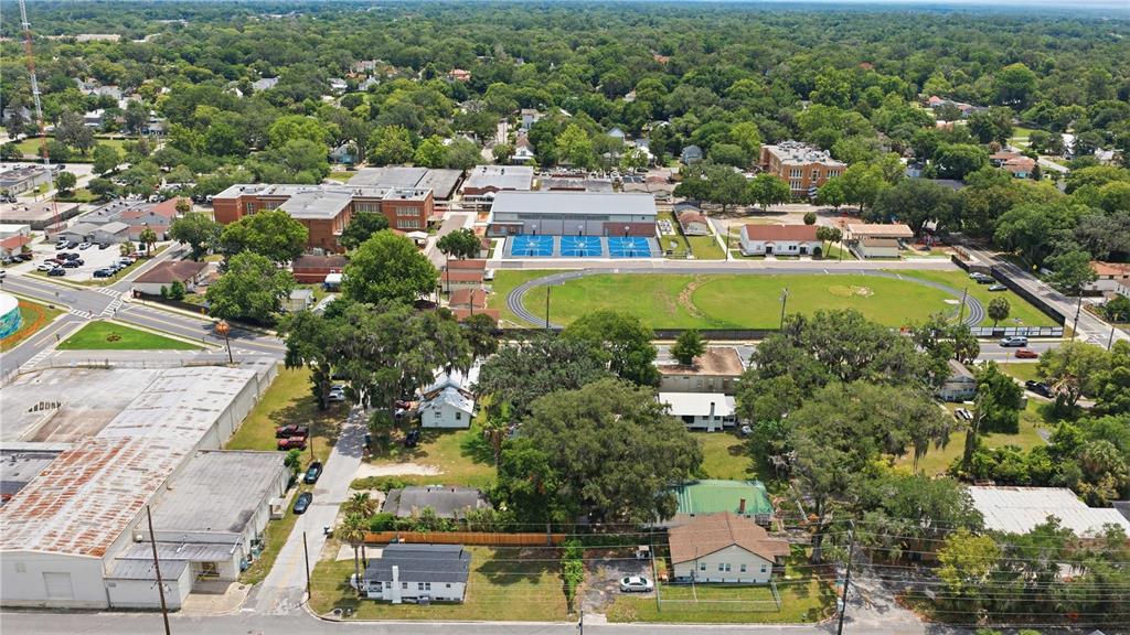An aerial view shows a school campus with a track, sports courts, and surrounding neighborhood — 1 CENTRAL WAREHOUSE, OCALA, FL