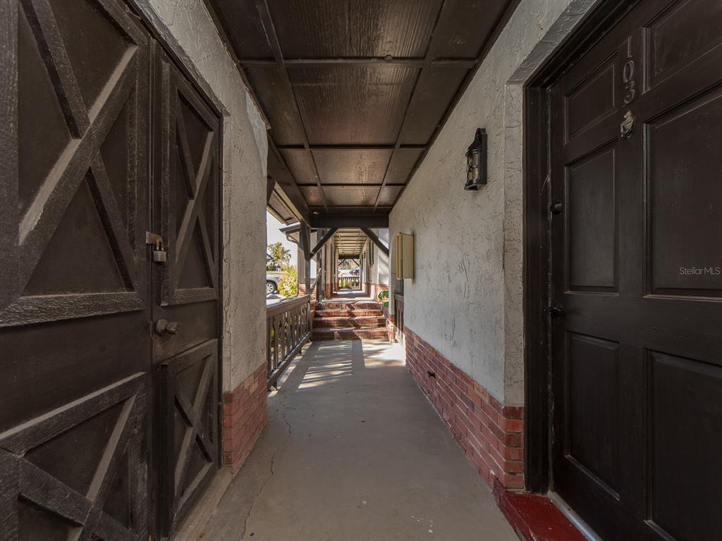 A covered outdoor walkway leads to a dark wooden door labeled 103 and a storage closet — 310 N BAYSHORE BOULEVARD UNIT 103, CLEARWATER, FL