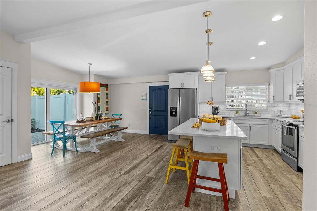 A bright kitchen and dining area with white cabinets, a central island, and wood flooring — 312 HARDIN AVENUE, ANNA MARIA, FL