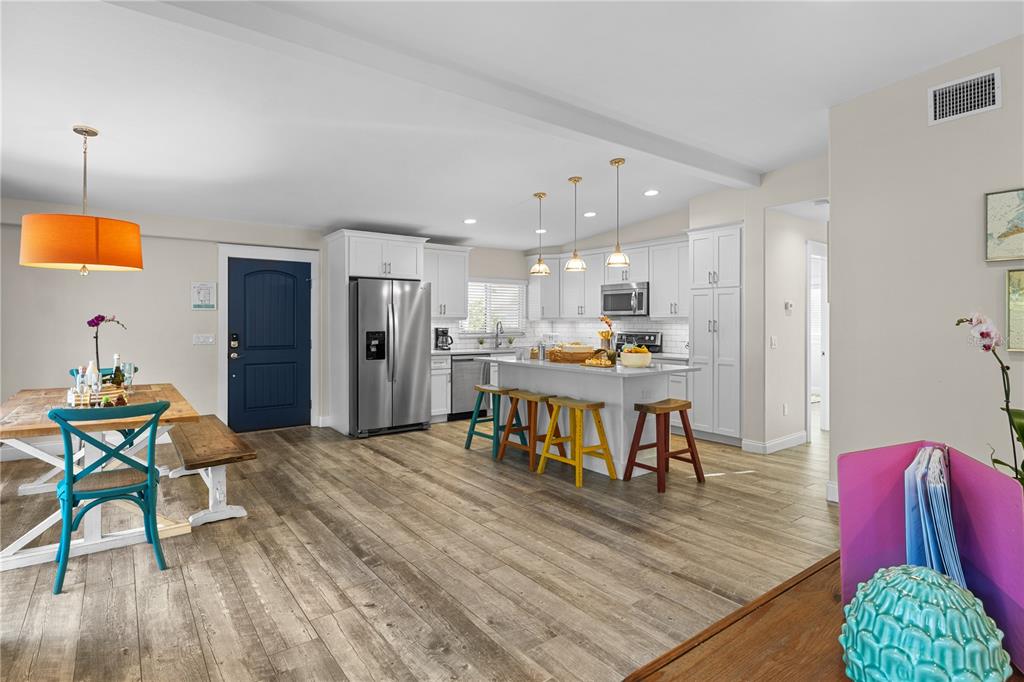 A kitchen and dining area feature white cabinetry, a central island, and wood-look flooring — 312 HARDIN AVENUE, ANNA MARIA, FL