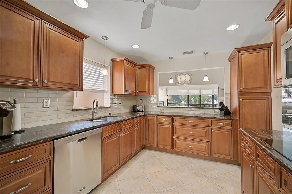 A kitchen with wood cabinets, granite countertops, stainless steel appliances, and light tile flooring — 6660 SCHOONER BAY CIRCLE UNIT 6660, SARASOTA, FL