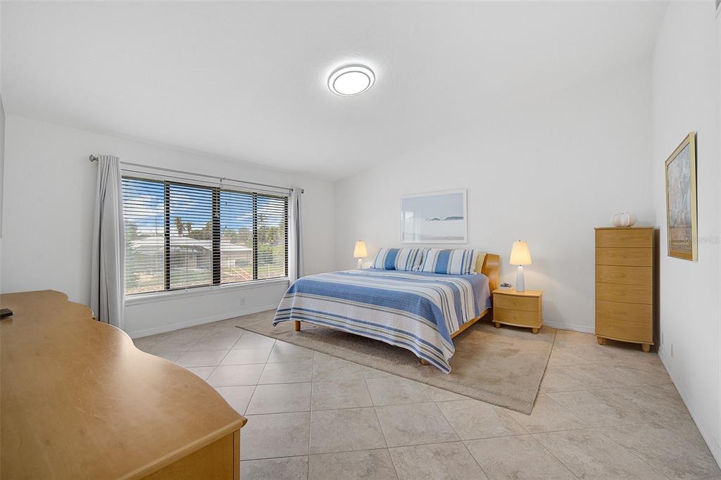 A bedroom with tile floors, a blue striped bed, and a large window — 6660 SCHOONER BAY CIRCLE UNIT 6660, SARASOTA, FL