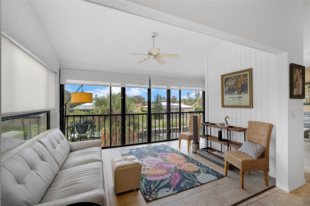 A sunroom features a white sofa, floral area rug, wicker chair, and large screened windows — 6660 SCHOONER BAY CIRCLE UNIT 6660, SARASOTA, FL