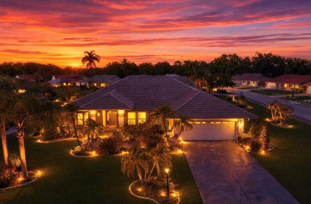 A single-story house with a tiled roof and illuminated landscaping at sunset — 2003 NEW BEDFORD DRIVE, SUN CITY CENTER, FL