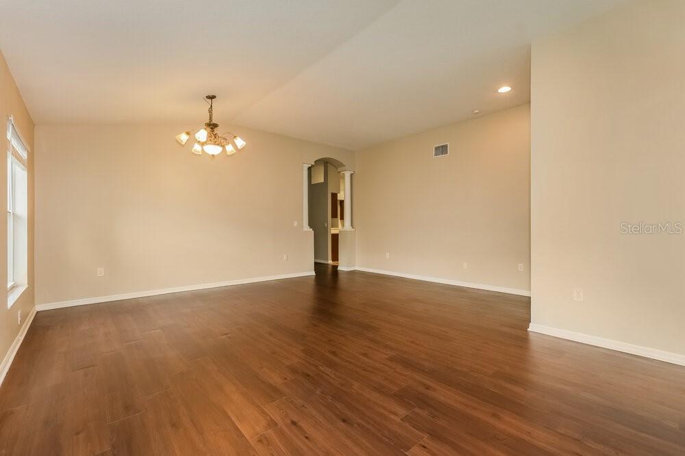 An empty room with light-colored walls, wood-look flooring, and a hanging chandelier — 812 LESA GLEN PLACE, BRANDON, FL