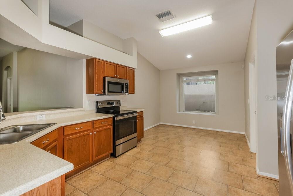 A kitchen with wood cabinets, stainless steel appliances, and tile flooring — 812 LESA GLEN PLACE, BRANDON, FL
