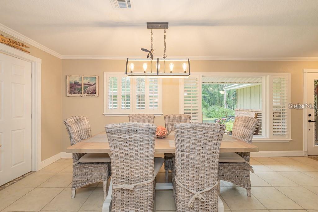 A dining room features a wooden table, six wicker chairs, and a rectangular pendant light — 3341 SE 45TH STREET, OCALA, FL