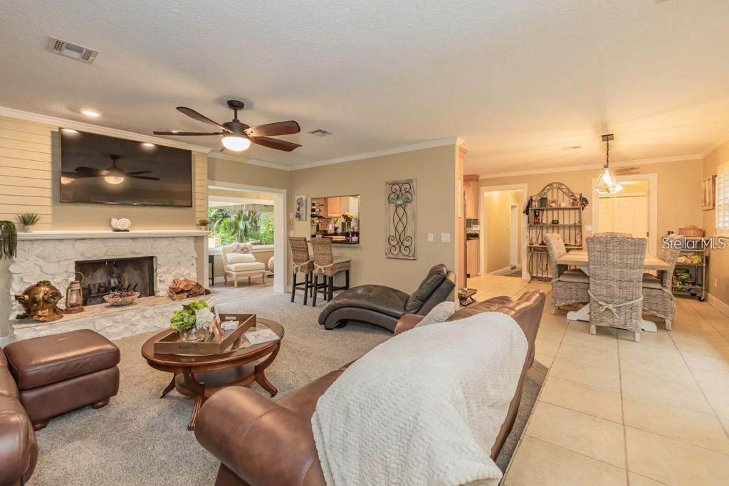 A living room with a stone fireplace, brown leather furniture, and an adjacent dining area — 3341 SE 45TH STREET, OCALA, FL