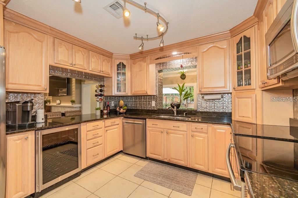 A kitchen with light wood cabinets, dark granite countertops, stainless steel appliances, and tile flooring — 3341 SE 45TH STREET, OCALA, FL