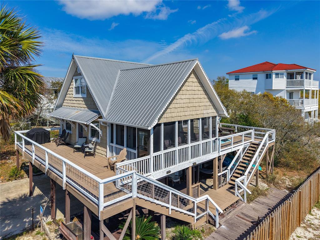 An elevated coastal house with a metal roof, wraparound deck, and screened-in porch — 7 BASS STREET, PANACEA, FL