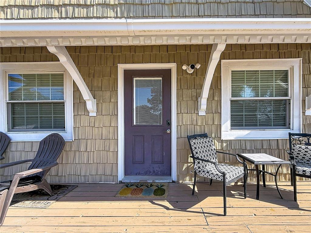 A wooden porch features a purple door, two windows, and outdoor seating furniture — 7 BASS STREET, PANACEA, FL