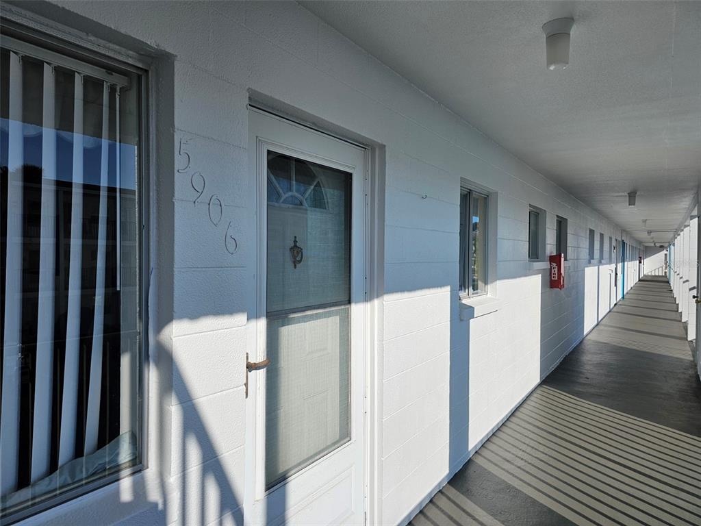 An exterior view of a white building with a long walkway and numbered doors — 5906 GARDEN LANE UNIT A22, BRADENTON, FL