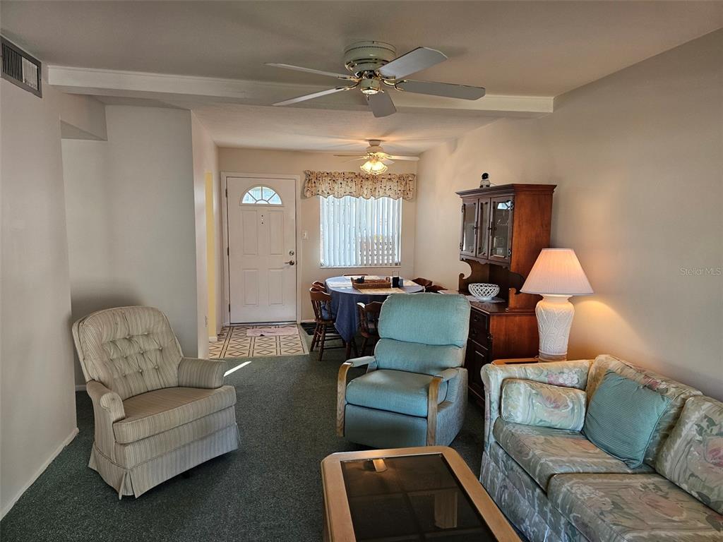 A dining area with a round table and hutch sits adjacent to a living room — 5906 GARDEN LANE UNIT A22, BRADENTON, FL