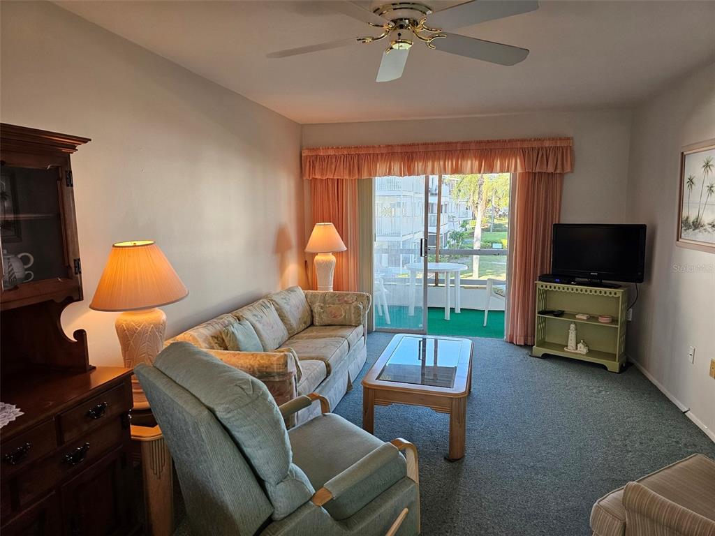 A dining area features a round table with a blue cloth, wooden chairs, and a window — 5906 GARDEN LANE UNIT A22, BRADENTON, FL