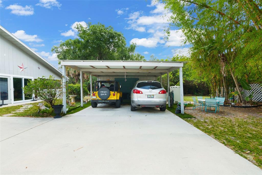 A concrete driveway leads to a covered carport sheltering a yellow Jeep and silver SUV — 2070 59TH STREET, SARASOTA, FL