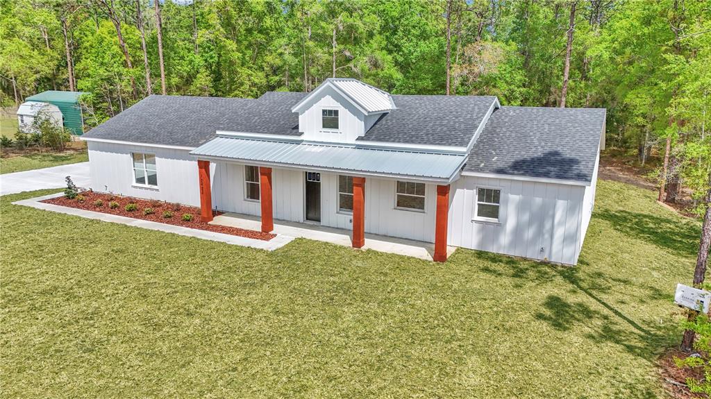 An aerial view of a white farmhouse with a metal roof and wooden porch columns — 12423 SW 45 STREET, OCALA, FL