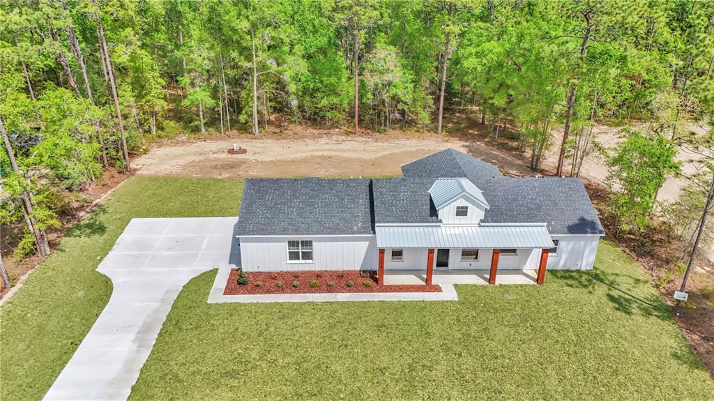 An aerial view of a white farmhouse with a metal roof and a concrete driveway — 12423 SW 45 STREET, OCALA, FL