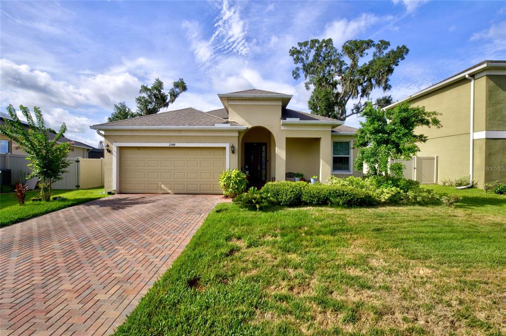 A single-story house with a brick driveway, a two-car garage, and a landscaped front yard — 2349 JERNIGAN LOOP, KISSIMMEE, FL