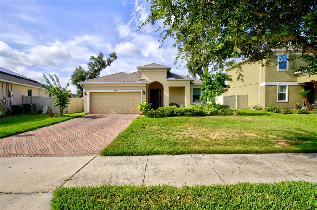 A single-story house with a brick driveway, a two-car garage, and a green lawn — 2349 JERNIGAN LOOP, KISSIMMEE, FL