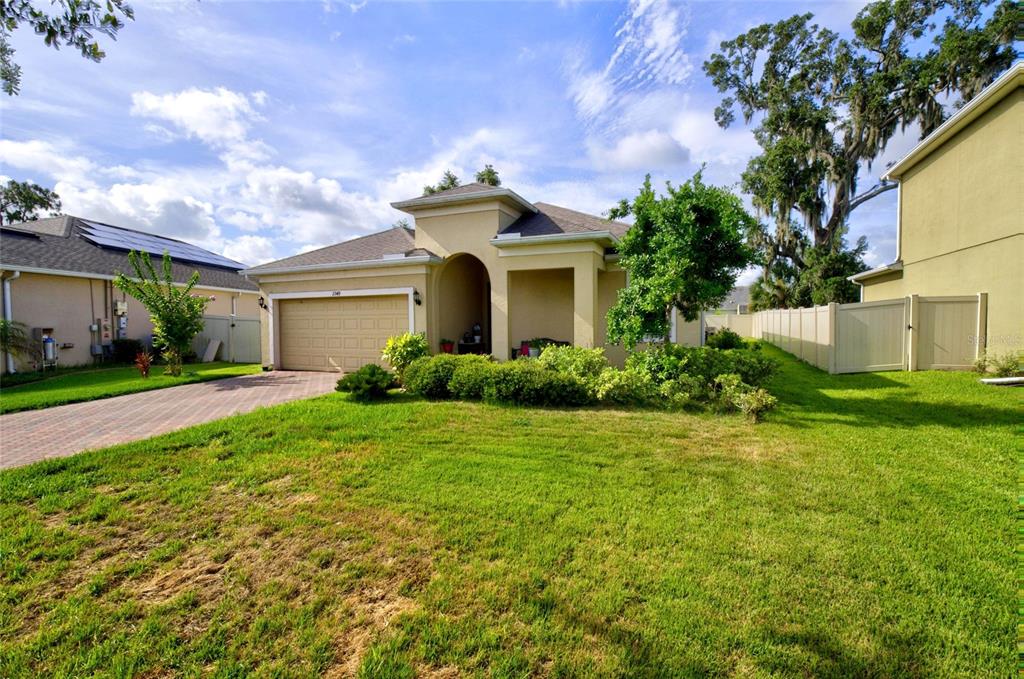 A single-story tan house with a two-car garage and a paved driveway — 2349 JERNIGAN LOOP, KISSIMMEE, FL