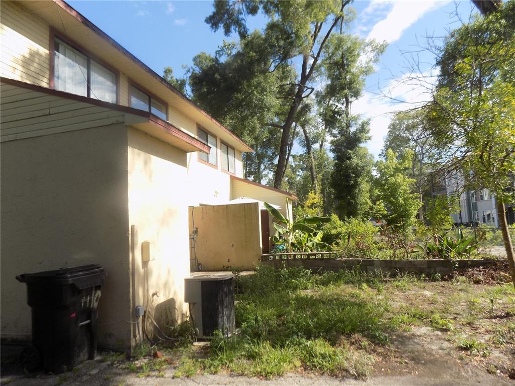 The exterior of a yellow house features a black trash bin and an air conditioning unit — 1110 SW 62 TERRACE UNIT A,B,C,D,E and F, GAINESVILLE, FL