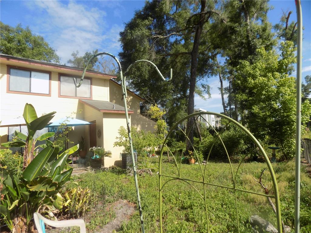 A backyard view features a two-story house, a metal garden arch, and a shepherd's hook — 1110 SW 62 TERRACE UNIT A,B,C,D,E and F, GAINESVILLE, FL