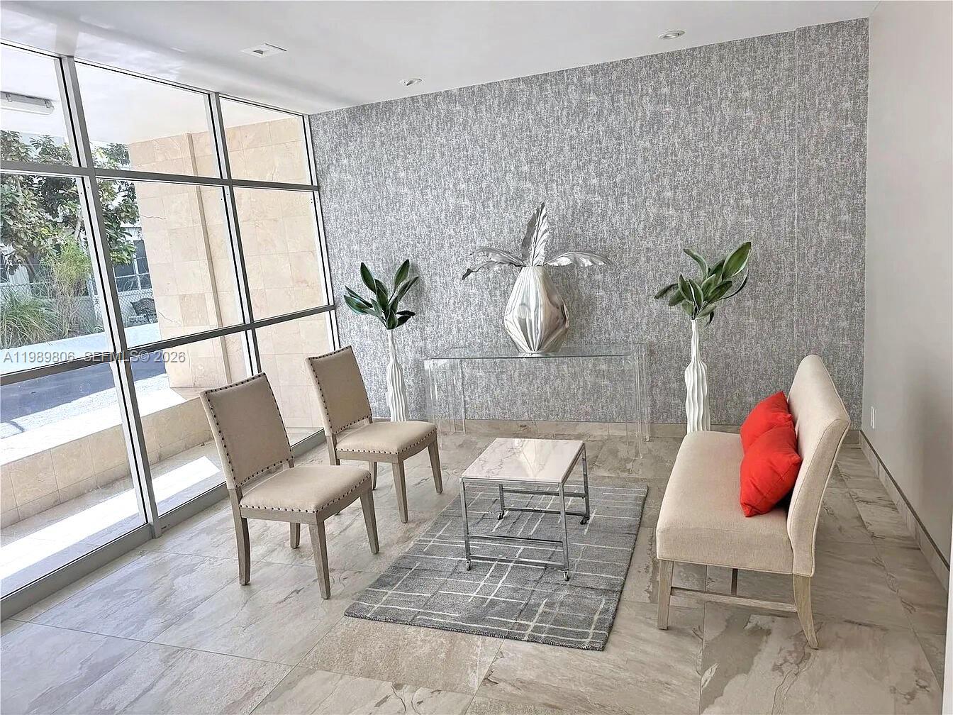 A modern lobby features a seating area with two chairs, a bench, and a coffee table — 3113 S Ocean Dr # 504, Hallandale Beach FL 33009, HALLANDALE BEACH, FL