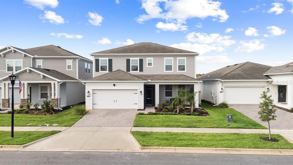 A two-story suburban house with a white garage, gray siding, and a paved driveway — 3204 ARMSTRONG AVENUE, CLERMONT, FL