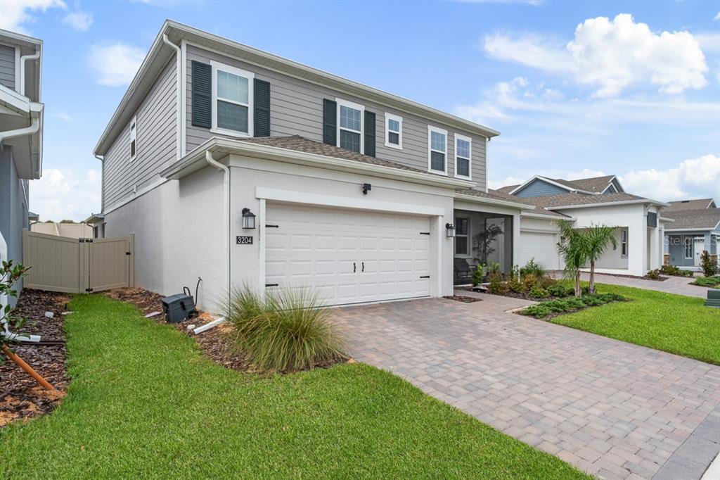 A two-story house with gray siding, a white stucco garage, and a paved driveway — 3204 ARMSTRONG AVENUE, CLERMONT, FL