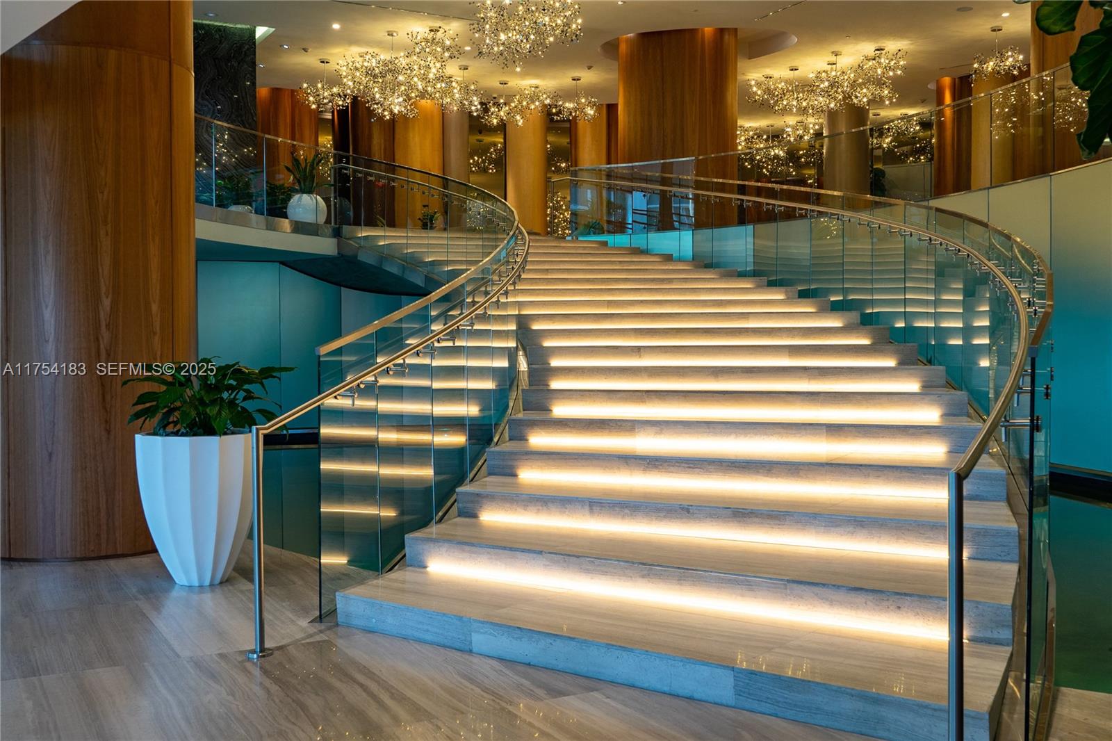 A grand staircase with illuminated steps and glass railings sits in a modern lobby — 488 NE 18 St # 1809, Miami FL 33132, MIAMI, FL