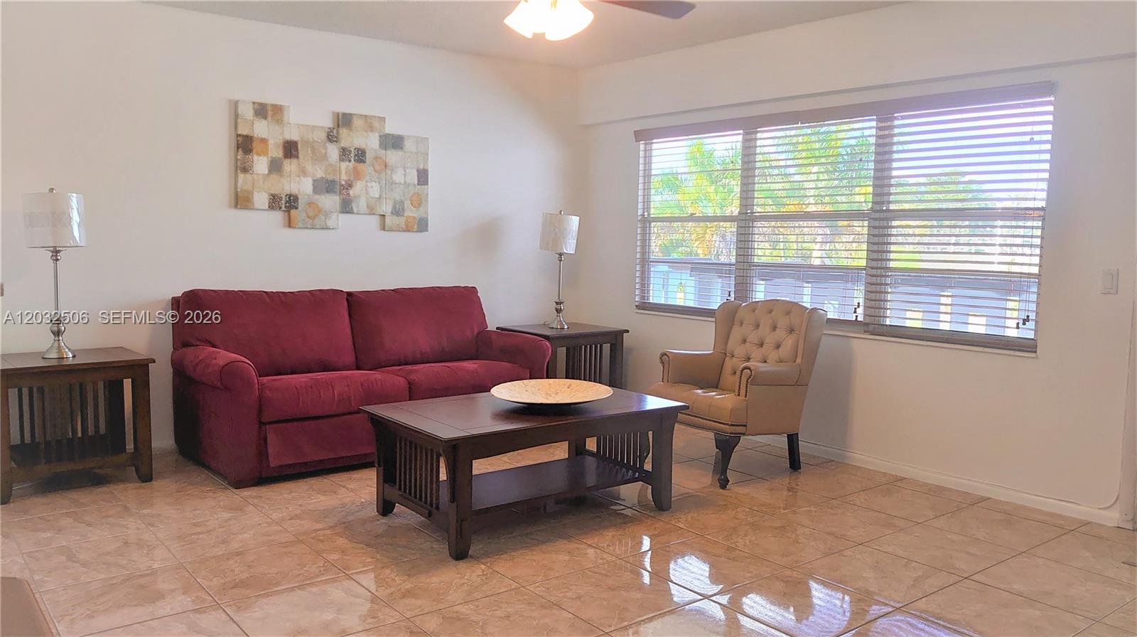 A living room features a red sofa, a beige armchair, and tile flooring — 250 Suffolk F # 250, Boca Raton FL 33434, BOCA RATON, FL
