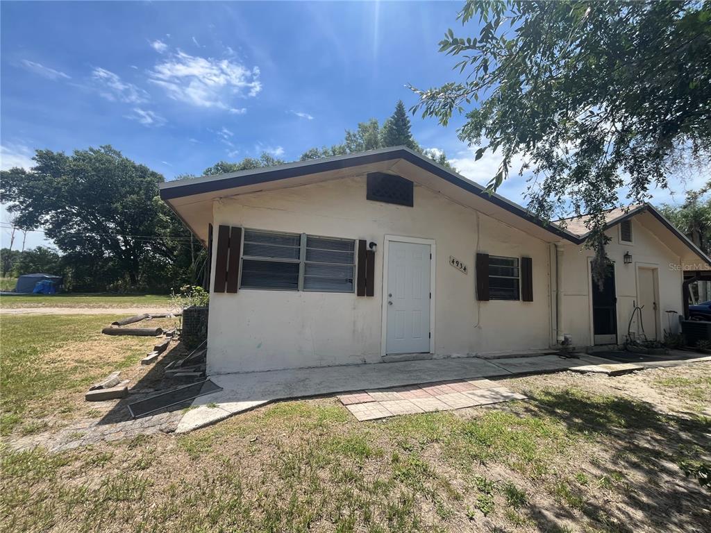 A single-story house with a white exterior, a front door, and windows with brown shutters — 4934 ADDESSI LOOP, LAND O LAKES, FL