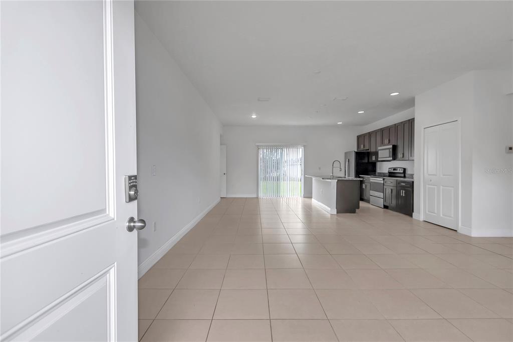 An open-concept kitchen and living area features tile flooring, dark cabinetry, and a sliding door — 3650 SW 128TH PLACE, OCALA, FL