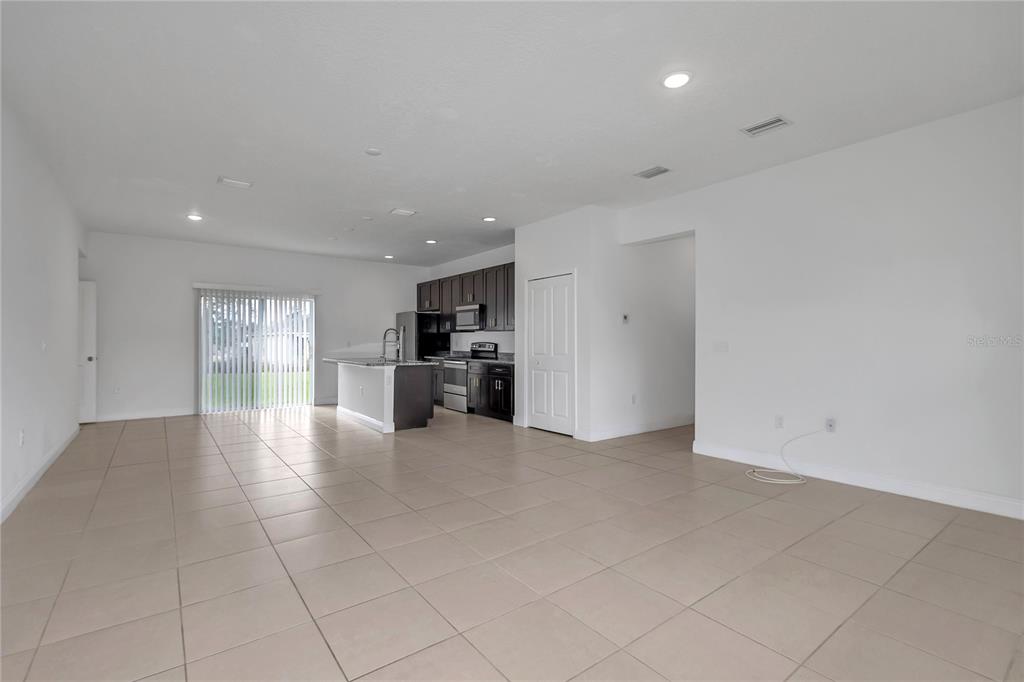 An open-concept kitchen with dark cabinets and an island overlooks a large tiled living area — 3650 SW 128TH PLACE, OCALA, FL