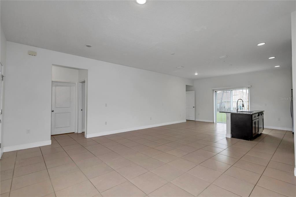An open-concept living area features light-colored tile flooring, white walls, and a kitchen island — 3650 SW 128TH PLACE, OCALA, FL