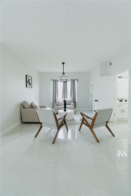 A bright living room features light tile floors, neutral furniture, and a modern chandelier — 1014 CORVINA DRIVE, DAVENPORT, FL