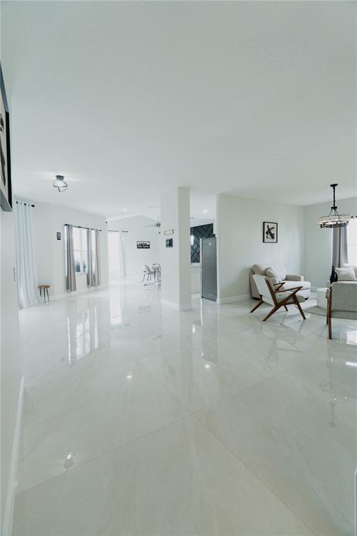 A bright, open-concept living area features white tile flooring, neutral walls, and modern light fixtures — 1014 CORVINA DRIVE, DAVENPORT, FL