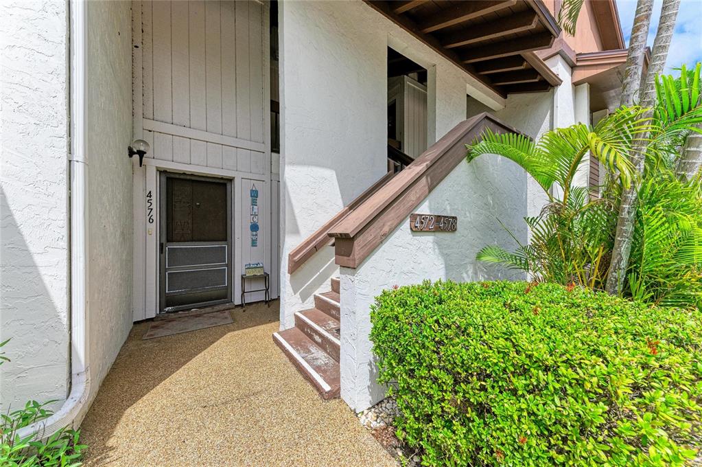An exterior view shows a building entrance with a screen door, stairs, and landscaping — 4578 RED MAPLE ROAD UNIT 904, BRADENTON, FL