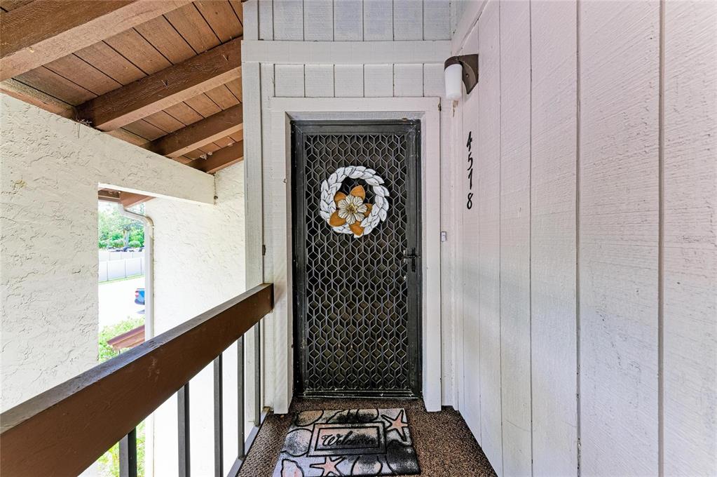 An exterior view of a front door with a security screen and a welcome mat — 4578 RED MAPLE ROAD UNIT 904, BRADENTON, FL
