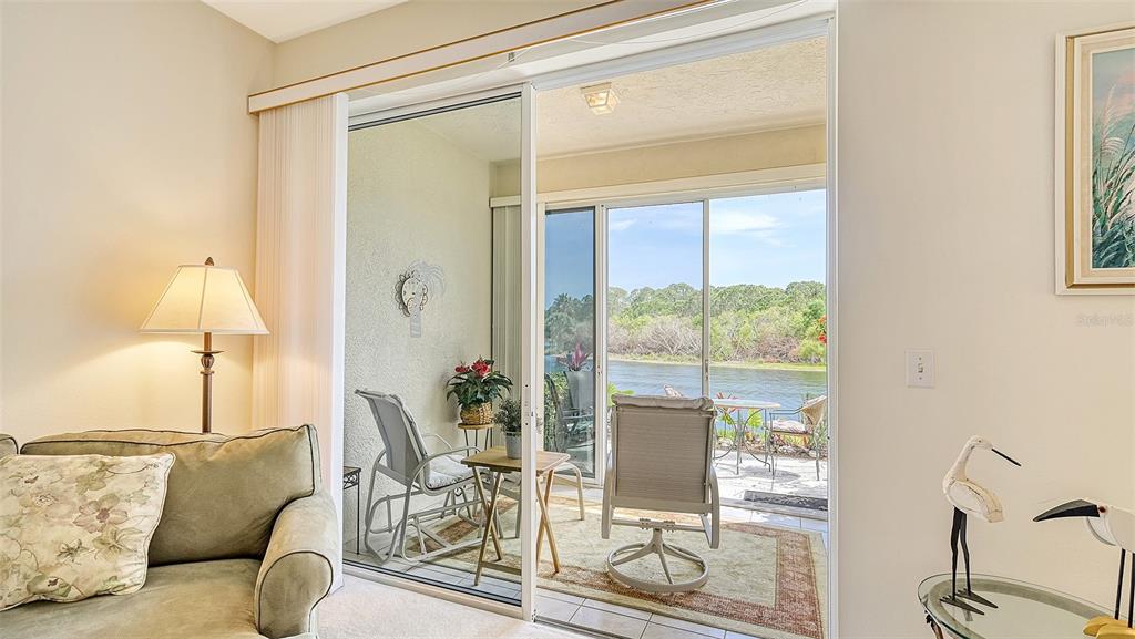 A living room with a sliding glass door opening to a patio overlooking a canal — 8350 WINGATE DRIVE UNIT 913, SARASOTA, FL