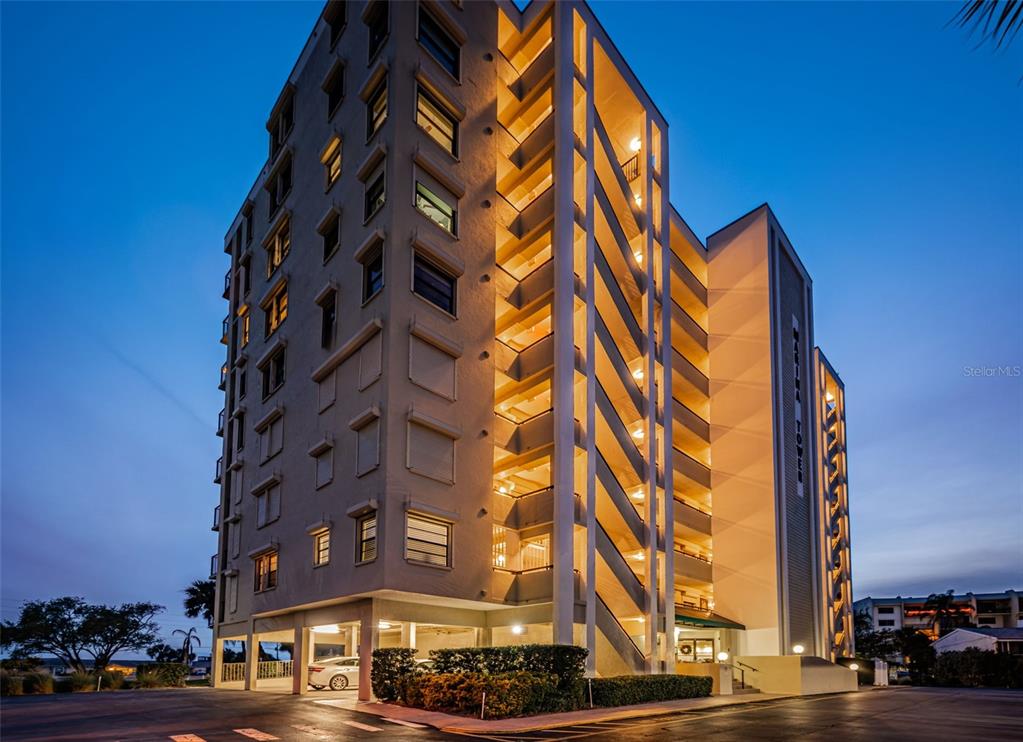 A multi-story apartment building with exterior stairwells and parking underneath at dusk — 2530 GARY CIRCLE UNIT 802, DUNEDIN, FL