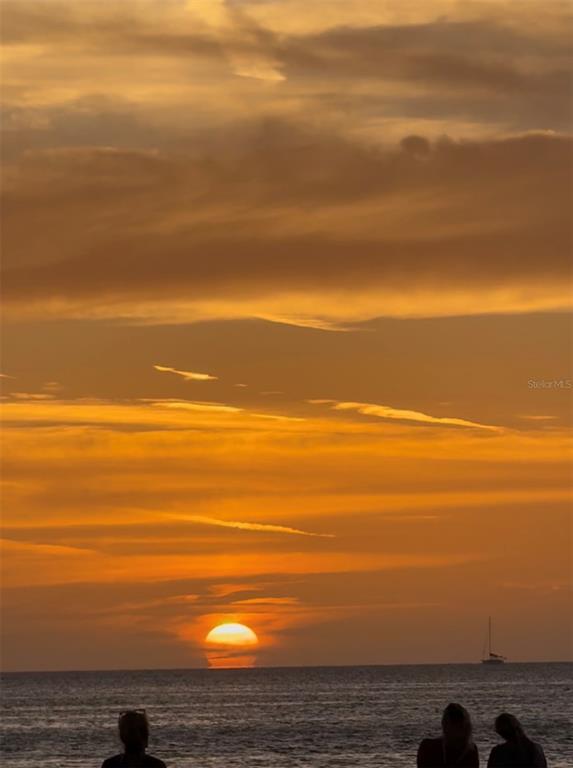 A sunset view over the ocean with a sailboat and silhouettes of people on shore — 2530 GARY CIRCLE UNIT 802, DUNEDIN, FL