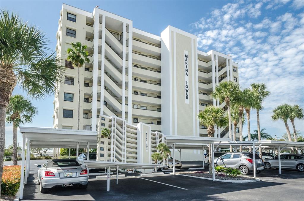 An exterior view of the Marina Tower apartment building with a covered parking area in front — 2530 GARY CIRCLE UNIT 802, DUNEDIN, FL