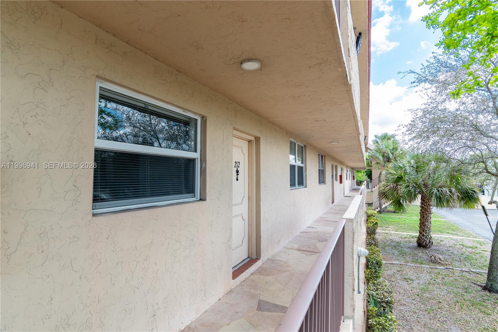 An exterior walkway with a stone floor leads past apartment doors and windows — 3900 NW 76th Ave # 212, Sunrise FL 33351, SUNRISE, FL