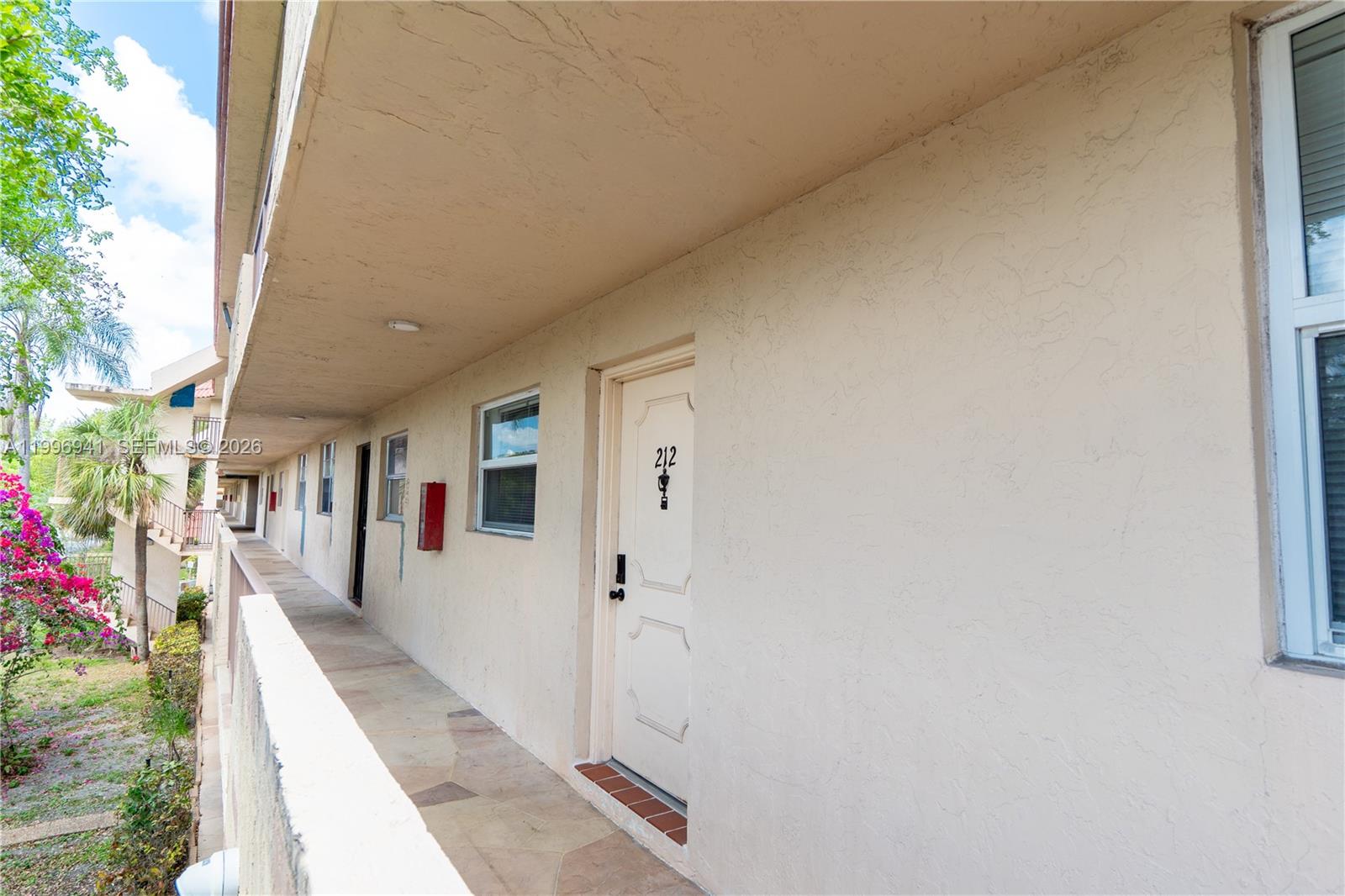 An exterior walkway leads past several apartment doors with unit number 212 in the foreground — 3900 NW 76th Ave # 212, Sunrise FL 33351, SUNRISE, FL