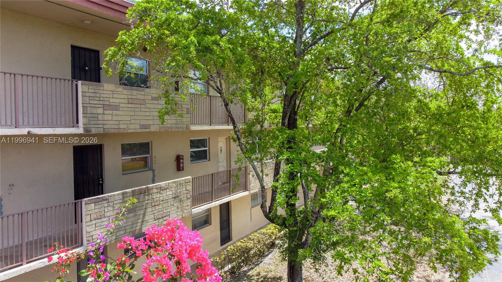 An exterior view shows a multi-story apartment building with balconies, stone accents, and a tree — 3900 NW 76th Ave # 212, Sunrise FL 33351, SUNRISE, FL