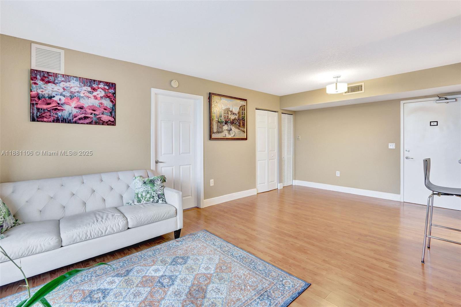 A living room features light wood flooring, a tufted sofa, and two framed wall paintings — 816 NW 11th St # 905, Miami FL 33136, MIAMI, FL