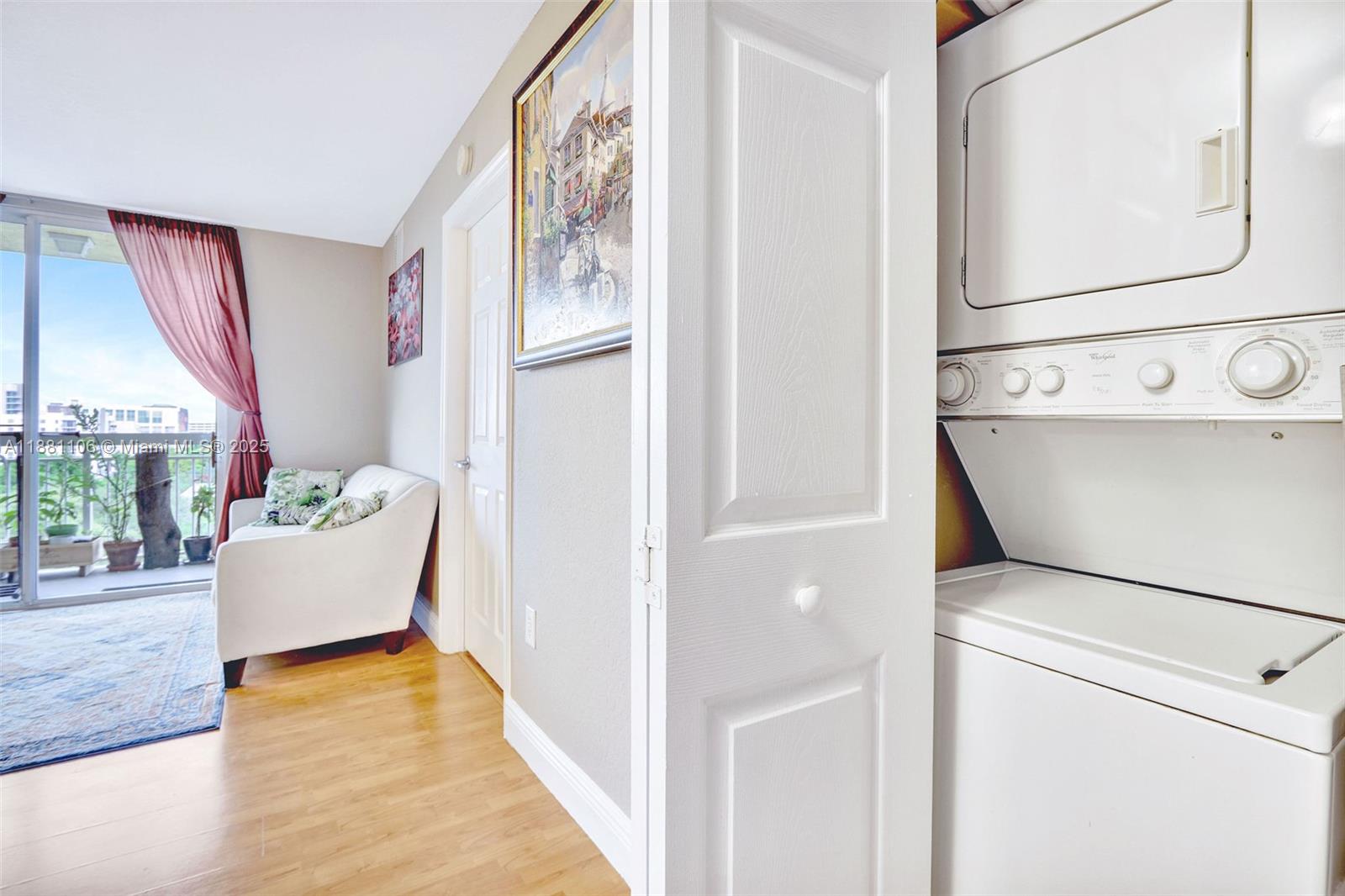 A laundry closet with a stacked washer and dryer sits beside a room with balcony access — 816 NW 11th St # 905, Miami FL 33136, MIAMI, FL